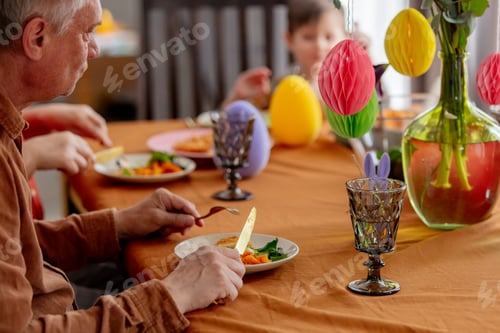 Preview: Grandpa eats at Easter dinner sitting at the table at home
