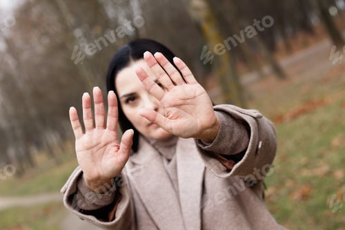 Preview: woman stretches her hands with open palms as a stop sign.