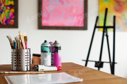 Preview: Interior view or art gallery with studio space, easels and cans of spray paint on a table.