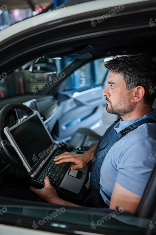 Preview: Auto mechanic is using a computer to diagnose problems in a car