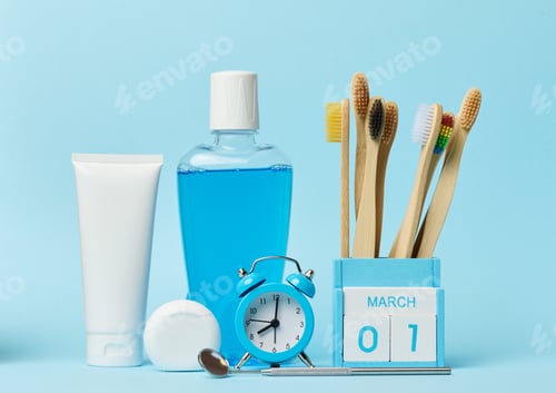 Preview: Mouthwash and toothpaste tube, alarm clock on blue background