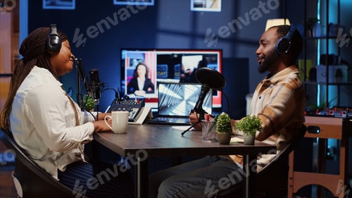 Preview: Show host recording podcast with guest, using audio recording equipment in home studio