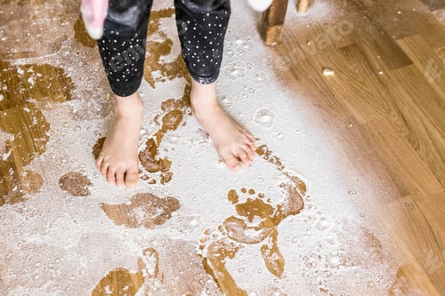 Preview: Low section of girl standing on flour covered floor at home