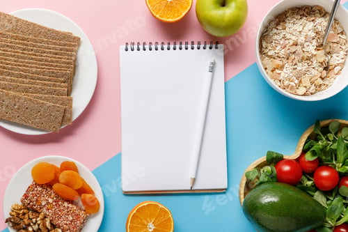 Preview: top view of empty notebook and pencil with tasty diet food on blue and pink background