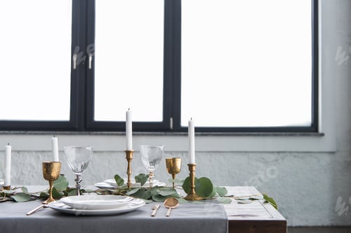 Preview: close up view of rustic table arrangement with eucalyptus, vintage tarnished cutlery, candles in