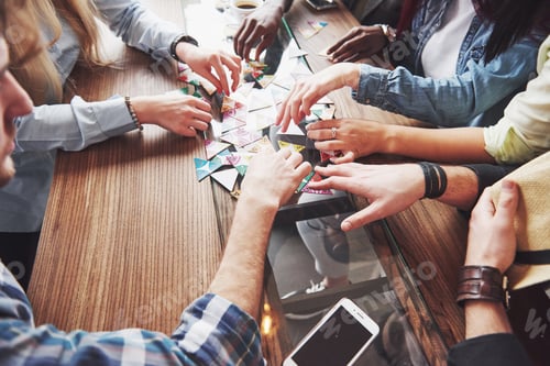 Preview: Group of creative friends sitting at wooden table. People having fun while playing board game