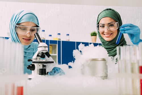 Preview: female muslim scientists in goggles experimenting with microscope and dry ice in chemical laboratory