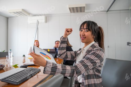 Preview: A business woman in the office shows her biceps and is happy with the business results