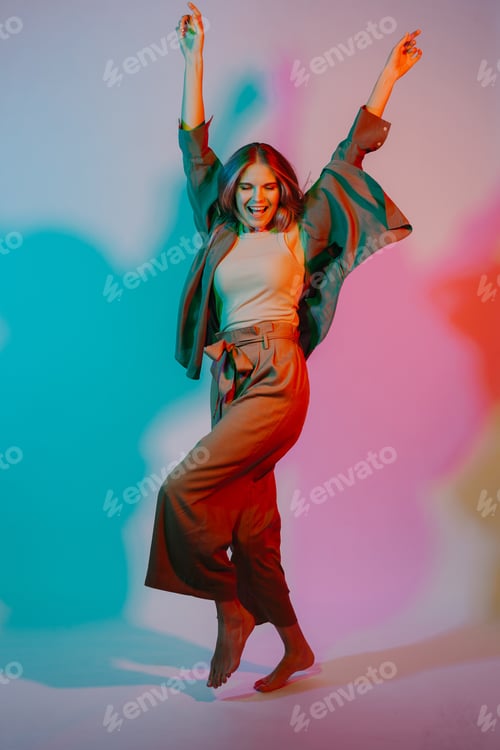 Preview: Woman jumping with joy under vibrant colored light