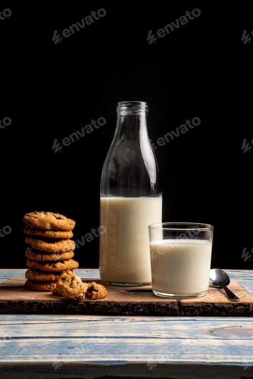 Preview: Milk and fresh cookies on board near napkin