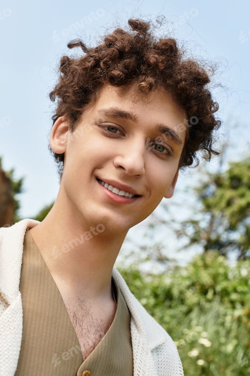 Preview: Young man enjoys sunny day in stylish outfit at vibrant green park