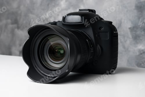 Preview: Black digital camera on a table with grunge background.