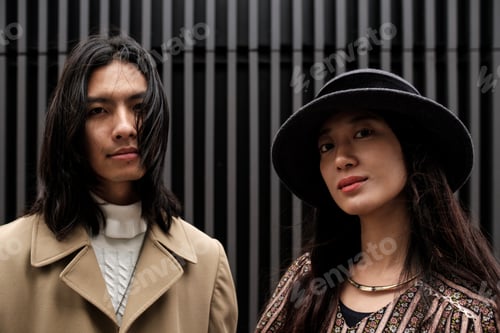 Preview: Fashionable asian couple posing against modern background