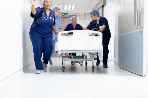 Preview: Diverse group of healthcare workers pushing patient in bed down hospital corridor, with copy space