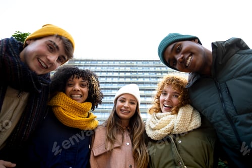 Preview: Low angle view of multiracial people having fun laughing outdoors looking at camera during winter