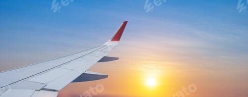 Preview: Plane wing view from airplane window inside against scenic sunset or sunrise sky background.