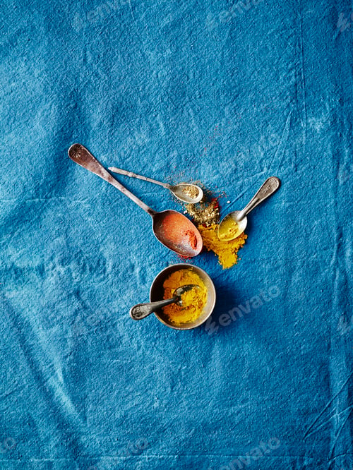 Preview: Spoons with spices on a blue textile surface.