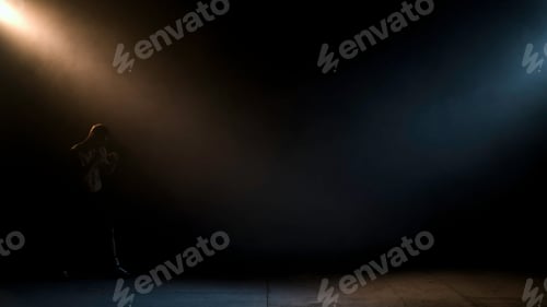 Preview: Boxer doing shadow Boxing in a dark room. Man of athletic build makes a punch. Dramatic lighting