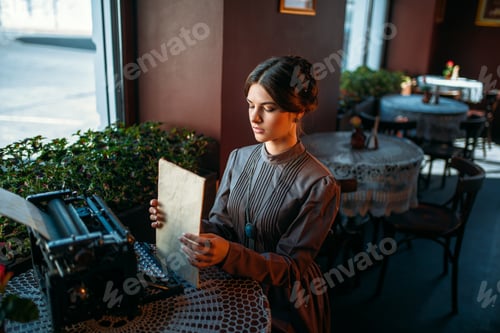 Preview: Happy young woman sits by the table in cafe