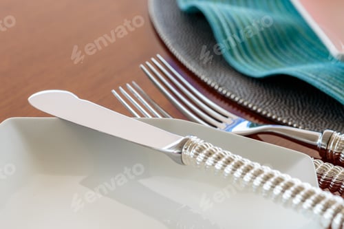 Preview: Closeup sot of a knife on a white plate near two works on a wooden table