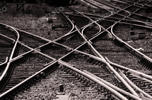 Preview: Closeup greyscale of different connected railway tracks at a station in greyscale
