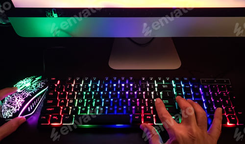 Preview: Generation z fingers on neon lights playing video games at his desk on computer.