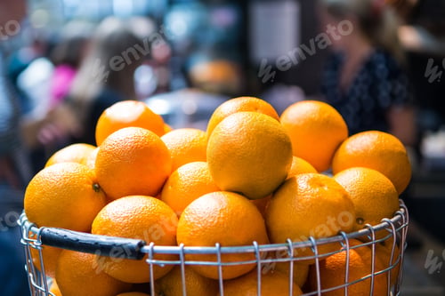 Preview: selective focus of pile of oranges in metal basket on blurred background