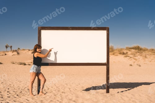 Visualização: mulher apontando para uma placa na praia