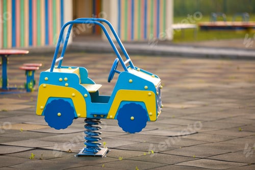 Preview: Kindergarten playground with bright toy car on spring. Children activities and recreation outdoors