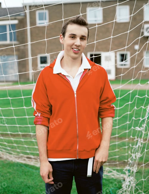 Preview: Confident young man standing in front of a soccer net, smiling