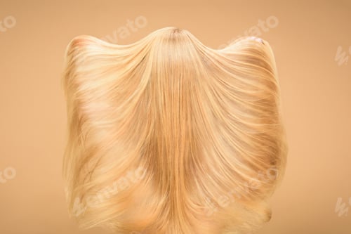Preview: Back view of woman playing with her long hair on beige background