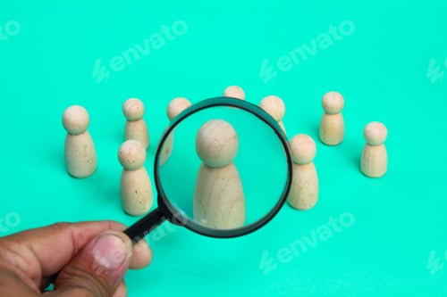 Preview: a wooden figure with a magnifying glass looking for a female worker.