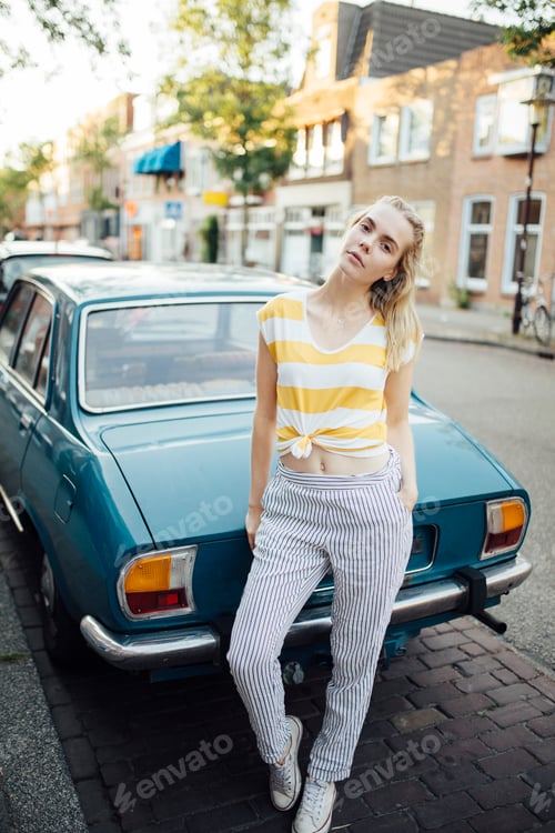 Preview: Portrait of young woman standing in front of vintage car