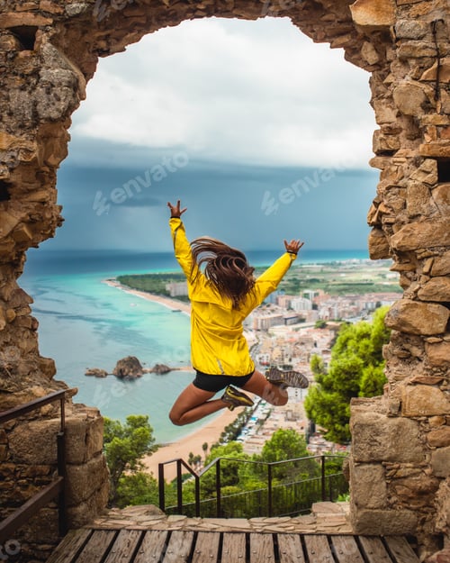 Preview: Girl jumping with excitement on a doorway with the sea in the background