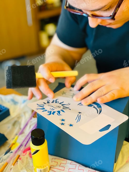 Preview: Woman stenciling on art project.