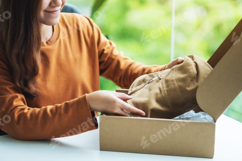 Preview: A woman receiving and opening a postal parcel box of clothing at home for online shopping