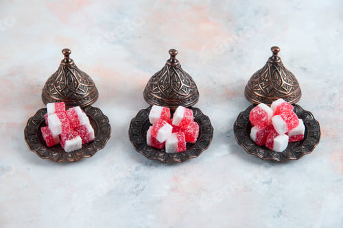 Preview: Candy crockery and pink candies in a row over white background