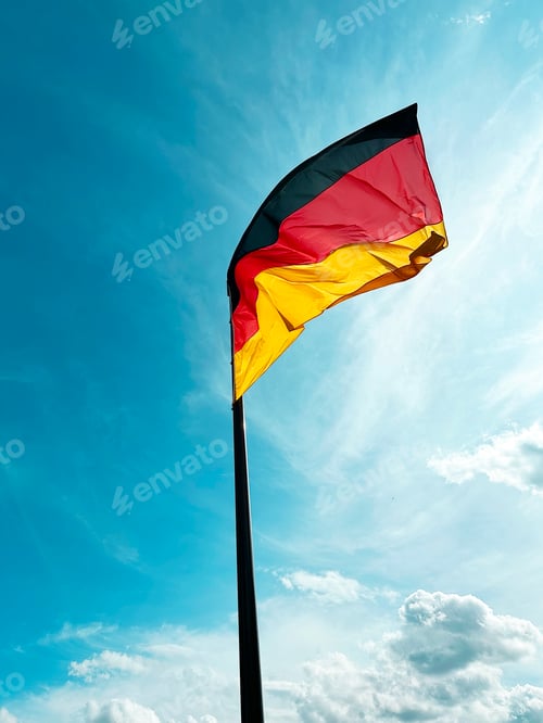 Preview: Colorful Black Red Yellow German Flag in Wind in Front of Blue Cloudy Sky