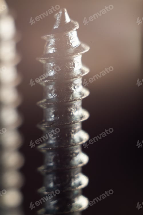 Preview: Vertical shot of different screws and bolts on a rough surface