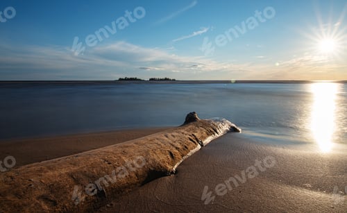 Preview: Beautiful sunrise on the sandy beach Ladoga lake with blue sky, surface and old wood