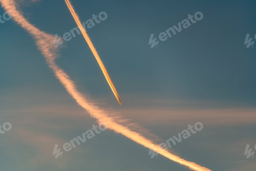 Preview: Airplane flying with condensation trails or contrail on the sky in the sunset