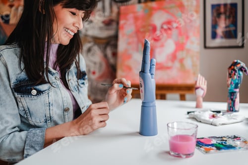 Preview: Happy artist painting wood art piece inside art home studio - Focus on left hand