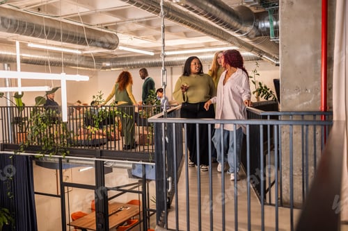 Preview: Coworkers walking and talking on elevated walkway in modern office