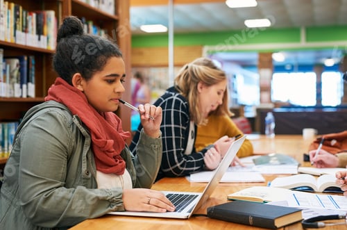 Preview: Shot of a focused young female student working on her laptop and studying inside of a library