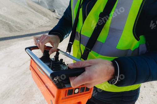 Preview: Construction worker operating machinery with remote control at concrete production plant