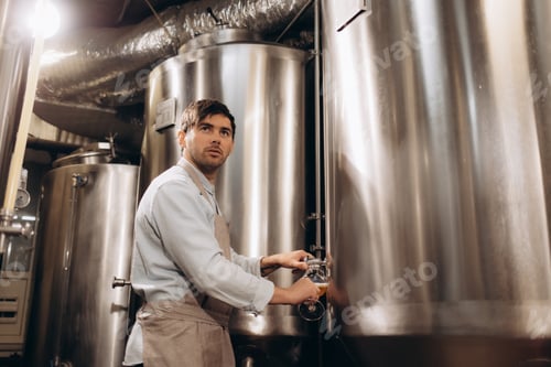 Preview: Brewer filling beer in bottle from tank at brewery