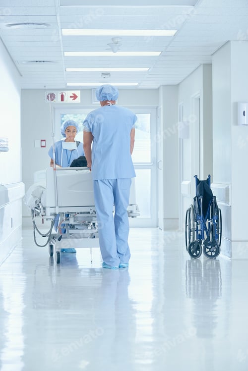 Preview: Male and female nurses pushing bed on hospital corridor