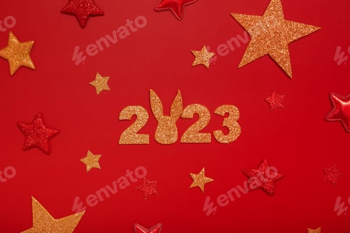 Conceito de flat lay de ano novo de 2023. Números 2023 com estrelas vermelhas e douradas, vista superior sobre fundo vermelho