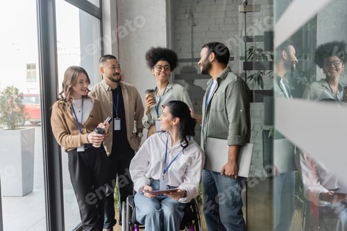 Preview: group shot of happy diverse team looking at each other in office, wheelchair user, inclusion