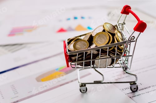 Preview: Cart full of euro coins on documents with graphs and economic data, defocused background.